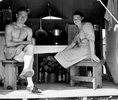 Julius and Agnes Antoniak sitting at a table inside a wooden-floored canvas temporary accommodation tent at Clyde Migrant Camp, Sydney, Australia in 1949.